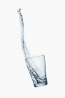 Primo piano vista di caduta bicchiere d'acqua su sfondo bianco — Foto stock