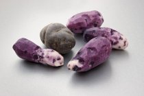Geschälte und ungeschälte violette Vitelotte-Kartoffeln — Stockfoto