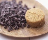 Closeup view of chocolate chips and brown sugar on wooden board — Stock Photo