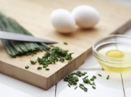Vista ravvicinata di uova ed erba cipollina su tavola di legno — Foto stock