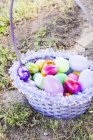 Vista elevada de una cesta de Pascua en el suelo con una variedad de huevos decorativos - foto de stock