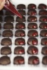 Наполнение шоколадных форм малиной — стоковое фото