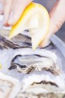 Hand squeezing lemon on oysters — Stock Photo