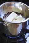 Vista de primer plano de la mantequilla de fusión y chispas de chocolate en olla en la estufa - foto de stock
