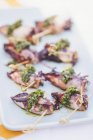 Closeup view of calamari appetizers with herbs on platter — Stock Photo