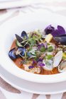 Closeup view of assorted shellfish in tomato broth with herbs — Stock Photo