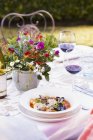 Outdoor table with mixed shellfish in tomato broth with herbs — Stock Photo