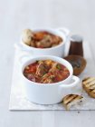 Turkey ragout with chorizo and tomatoes in white pots over desk — Stock Photo