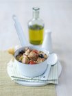 Рагу с грудью индейки, помидорами и оливками в белой миске над тарелкой — стоковое фото