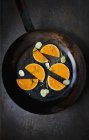 Slices of raw butternut squash with garlic and rosemary in an old frying pan — Stock Photo