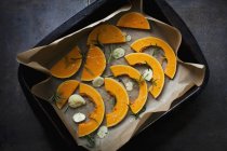Slices of raw butternut squash with garlic and rosemary in a roasting tin — Stock Photo
