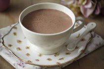 Vue rapprochée du cacao en tasse blanche avec cuillère sur soucoupe à motifs floraux et serviette — Photo de stock