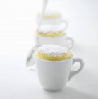 Vista de cerca de tres soufflés de limón con azúcar glaseado en tazas - foto de stock