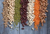 Assorted pulses in rows over wooden surface — Stock Photo