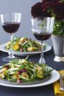 Salada de abúgula e copos de vinho tinto — Fotografia de Stock