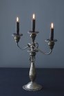 Vista de primer plano de un candelabro con tres velas encendidas oscuras - foto de stock