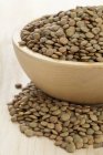Closeup view of dried green lentils in a wooden bowl — Stock Photo