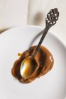 Closeup top view of Dulce de leche caramelised milk with spoon on white plate — Stock Photo