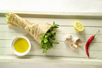 Herbs, chilli, garlic, lemon and olive oil on wooden surface — Stock Photo