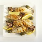 Vista superior de calamares a la parrilla con limones y alcaparras - foto de stock
