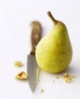 Fresh pear with knife and pieces of walnut — Stock Photo