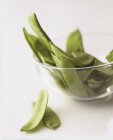 Fresh mange tout in a glass bowl on white background — Stock Photo