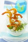 Deep-fried prawn skewers with rocket and fennel in glass bowl over plate — Stock Photo