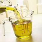 Verter aceite de oliva en la taza - foto de stock