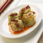 Quattro gnocchi di soia Shumai Edamame, su piatto bianco con olio di pepe rosso — Foto stock