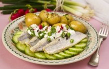 Herring with baby potatoes on plate over table with fork — Stock Photo