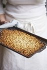 Woman holding baking sheet of nuts — Stock Photo