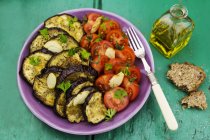 Piatto di verdure con pomodori e melanzane cariche su una superficie di legno verde — Foto stock