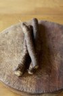 Tre pezzi di radice di bardana sul tagliere di legno — Foto stock