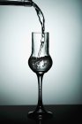 Vista close-up de derramar bebida transparente em vidro — Fotografia de Stock