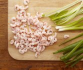 Shrimps and scallions on cutting board — Stock Photo