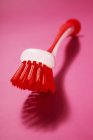 Closeup view of a one washing up brush on pink surface — Stock Photo