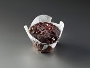 Muffin wrapped in baking parchment — Stock Photo