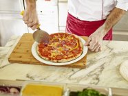 Koch schneidet Pizza — Stockfoto