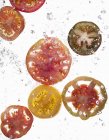 Fatias de tomates que caem na água — Fotografia de Stock