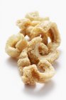 Closeup view of crispy bacon rinds on white surface — Stock Photo