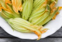 Fresh courgette flowers on plate — Stock Photo