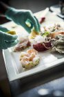 Uno chef che dispone un piatto di pesce su un piatto di porcellana bianca — Foto stock