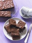 Brownies on wire rack and on white plate — Stock Photo