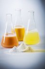 Still life with egg yolk, egg white and mixed egg in laboratory flasks and as powders — Stock Photo