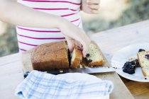 Closeup cropped view of child picking a slice of blackberry cake — Stock Photo