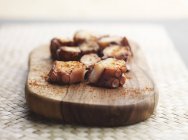 Vue rapprochée des tranches de poulpe galicien sur une planche de bois — Photo de stock
