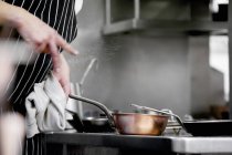 Шеф-повар нажимает соль на блюдо во время обслуживания в рабочем ресторане — стоковое фото