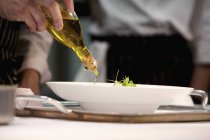 Closeup cropped view of person adding oil to dish — Stock Photo