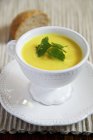Cream of yellow pepper soup in white pot over plate — Stock Photo