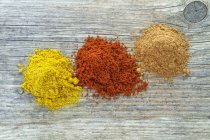Top view of three mounds of different spices on wooden surface — Stock Photo
